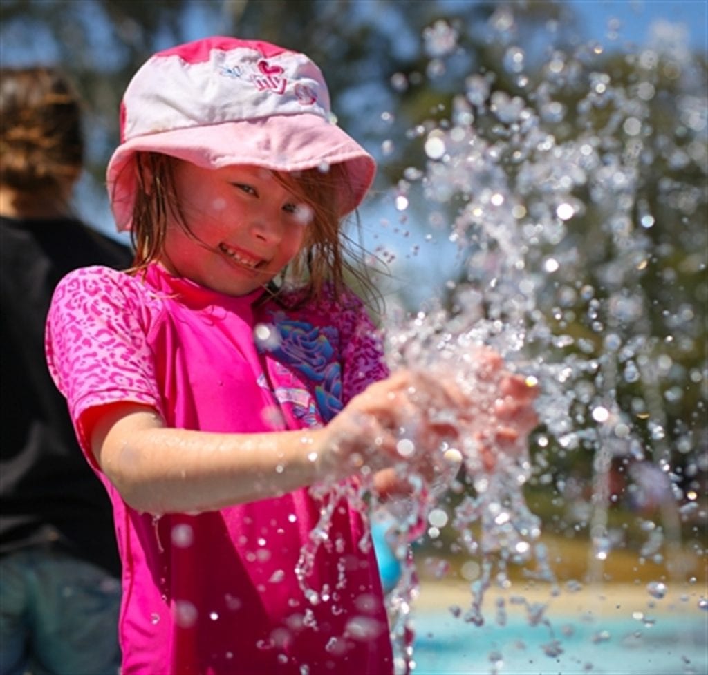 little girl playing in water outside